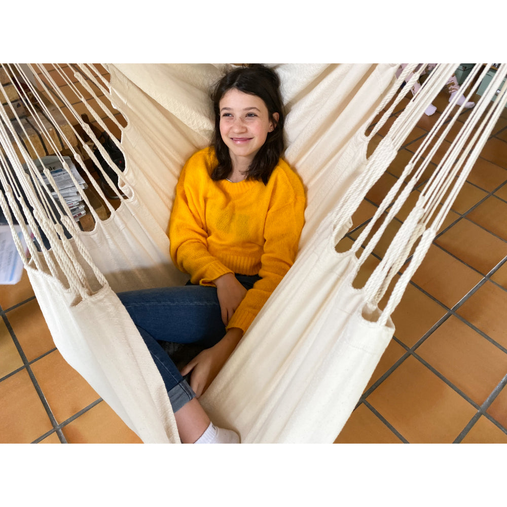 Young girl smiling and swinging in hammock