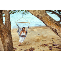 Woman reading a magazine in a hammock hung from a tree at the beach