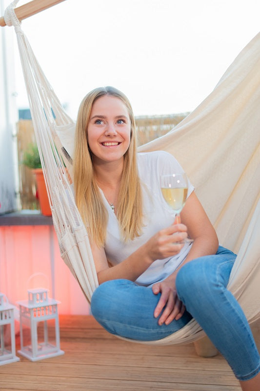 Woman relaxing with drink in beautiful white cotton hammock chair