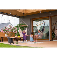 Family relaxing together in chair hammocks on porch.