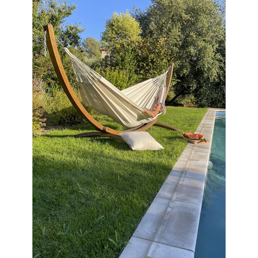 White hammock in wooden hammock frame beside swimming pool