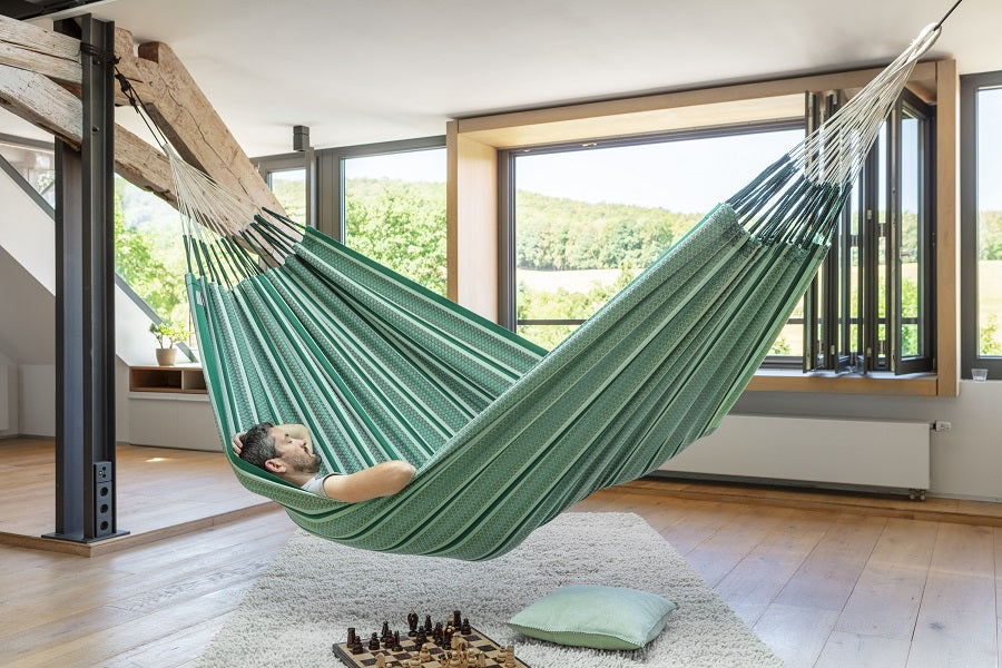 Green and white large organic cotton hammock suspended inside from beams