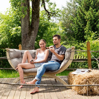 Couple sitting on a padded wooden sofa in a garden
