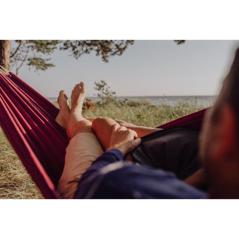 Person relaxing in a hammock with feet up, overlooking a natural landscape.