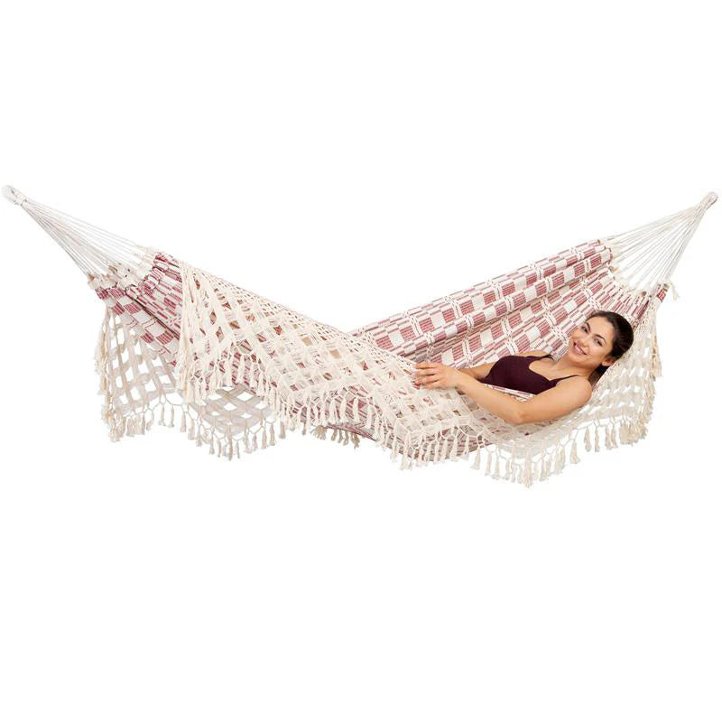Woman lying in a red and white patterned hammock on a white background