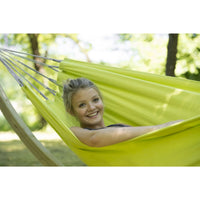 Woman relaxing in a bright green hammock with a blurred natural background