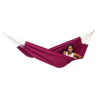 Person sitting in a red hammock with white ropes on a white background