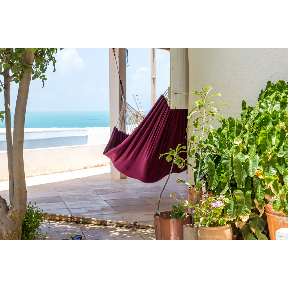 Maroon hammock hanging on a porch with ocean view