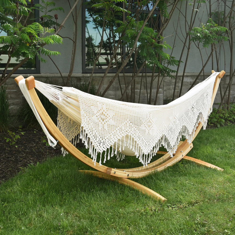 White crochet hammock on a wooden stand in a garden setting