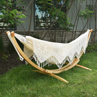 White crochet hammock on a wooden stand in a garden setting
