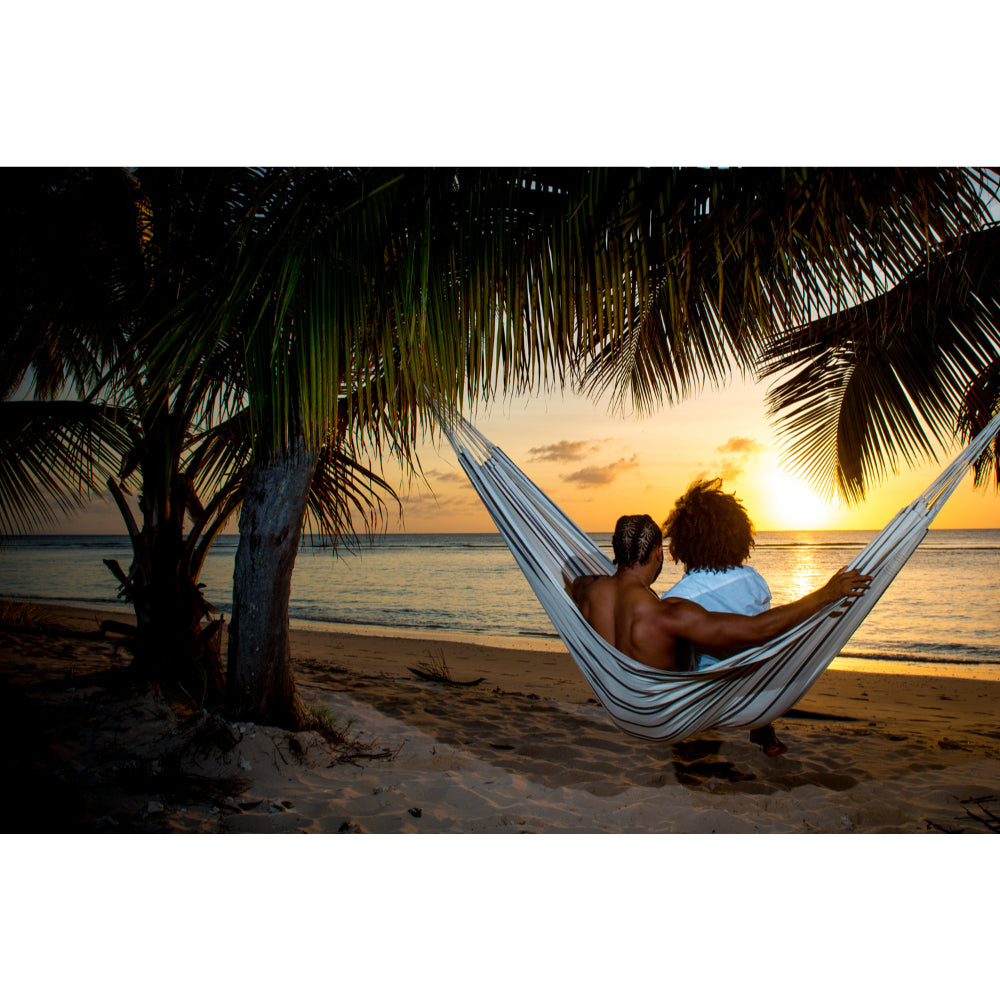 Couple relaxing in hammock watching the sunset on beach