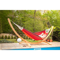 Two people relaxing in curved wooden hammock stand beside swimming pool
