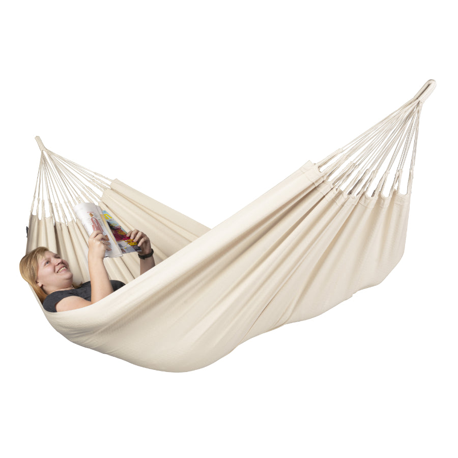 Woman reading a magazine in a white hammock