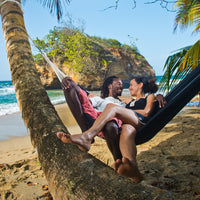 Couple resting in hammock on beach