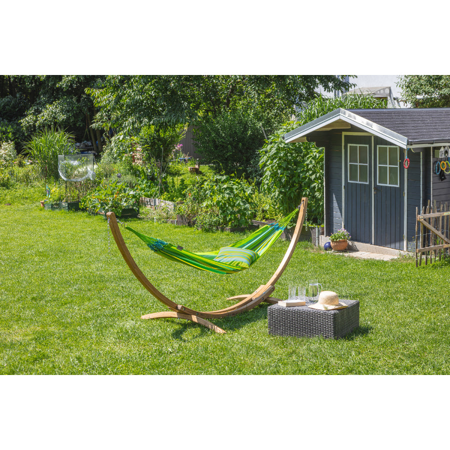 Green hammock set up on curved wooden hammock stand in garden setting