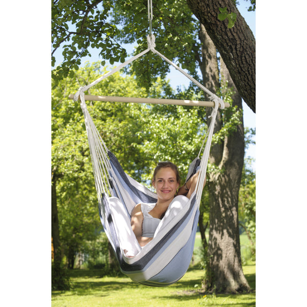 woman resting in hammock chair hung from tree branch